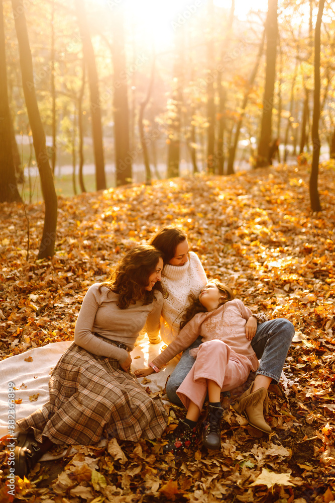 The homosexual family playing with her daughter in the autumn forest. The adventure is more fun when they are together. Autumn women.