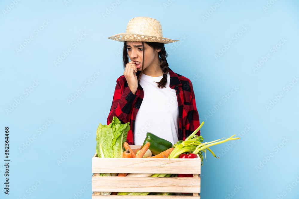 Young farmer Woman holding fresh vegetables in a wooden basket having doubts