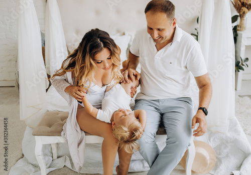 Parents playing with son sitting on the bed. photo