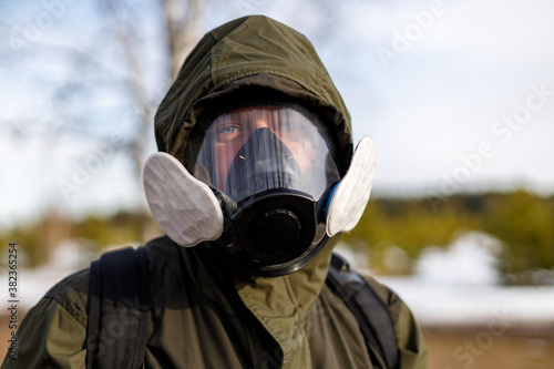a man in a protective mask from gases looks into the frame against the background of nature © metelevan
