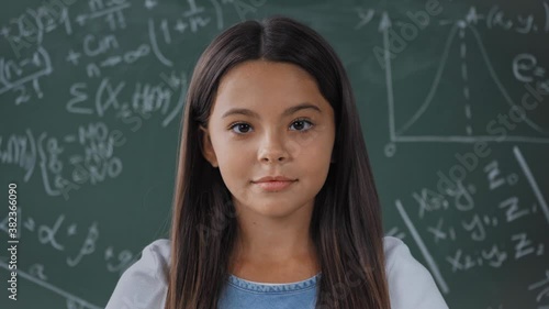 joyful schoolkid looking at camera near chalkboard