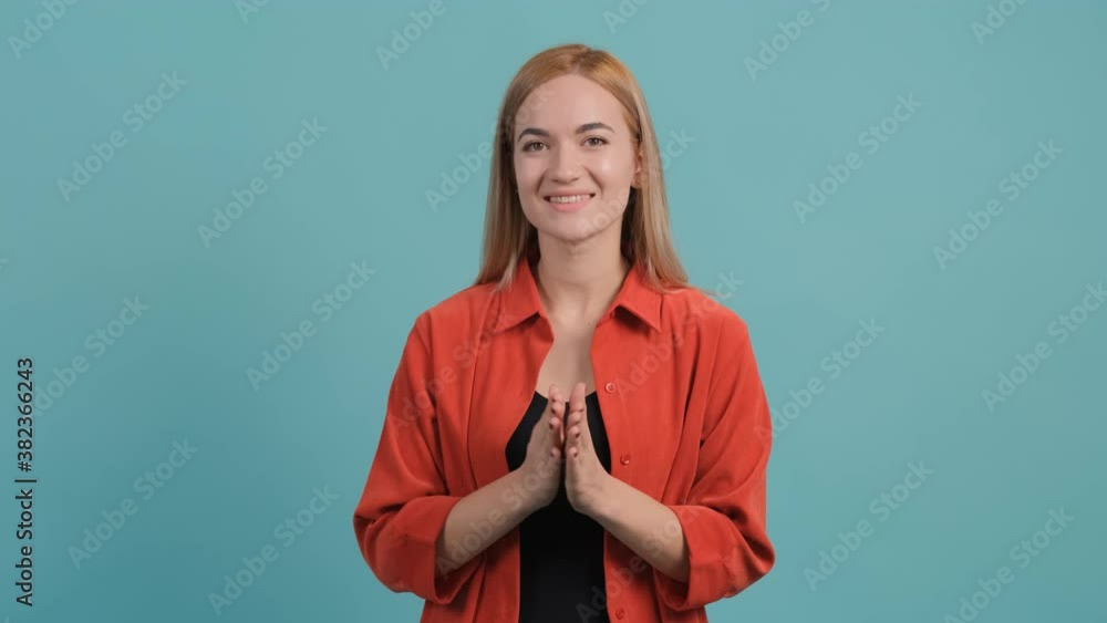 Close up of a pretty girl with blond hair clapping as she sits on the turquoise background. Close up of a pretty girl with blond hair clapping as she sits on the turquoise background.