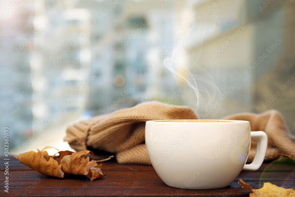 Cup of hot coffee and autumn leaves on window sill indoors. Space for text - obrazy, fototapety, plakaty 