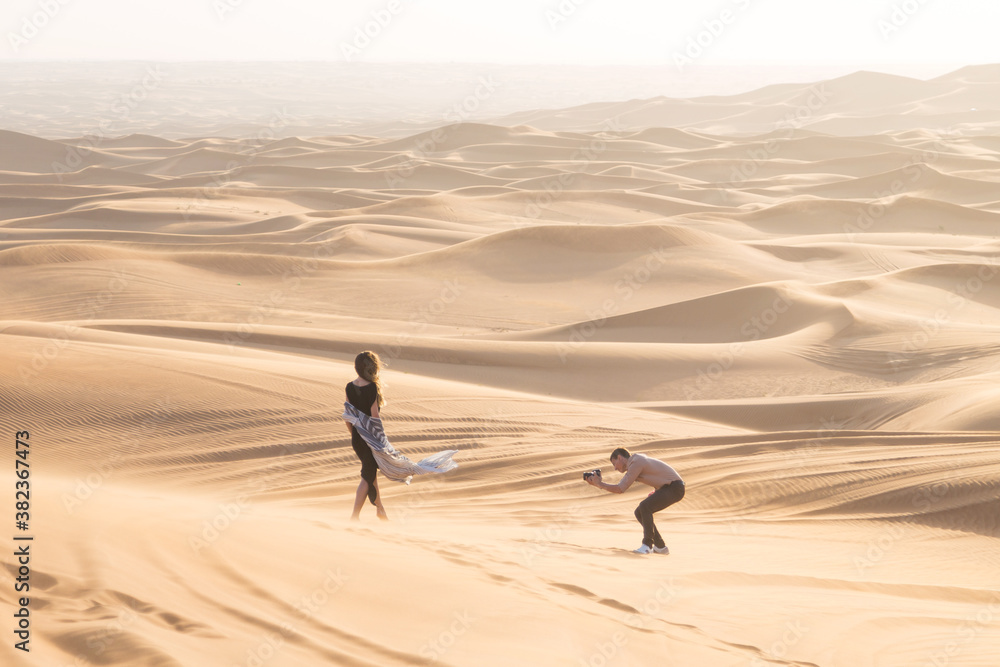 Exclusive photo shoot of a woman in the desert. Magazine advertising filming. The work of the photographer and model in desert of Dubai.