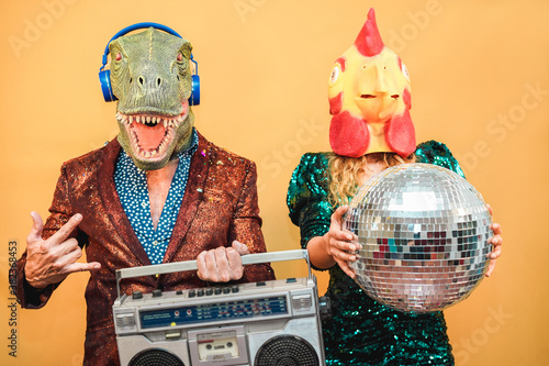 Crazy stylish people listening music with vintage boombox stereo - Fashion couple wearing t-rex and chicken mask at party fest event - Absurd, holidays and funny trend concept - Focus on man face