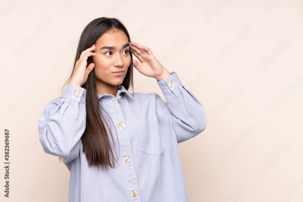 Young Indian woman isolated on beige background having doubts and thinking Young Indian woman isolated on beige background having doubts and thinking
