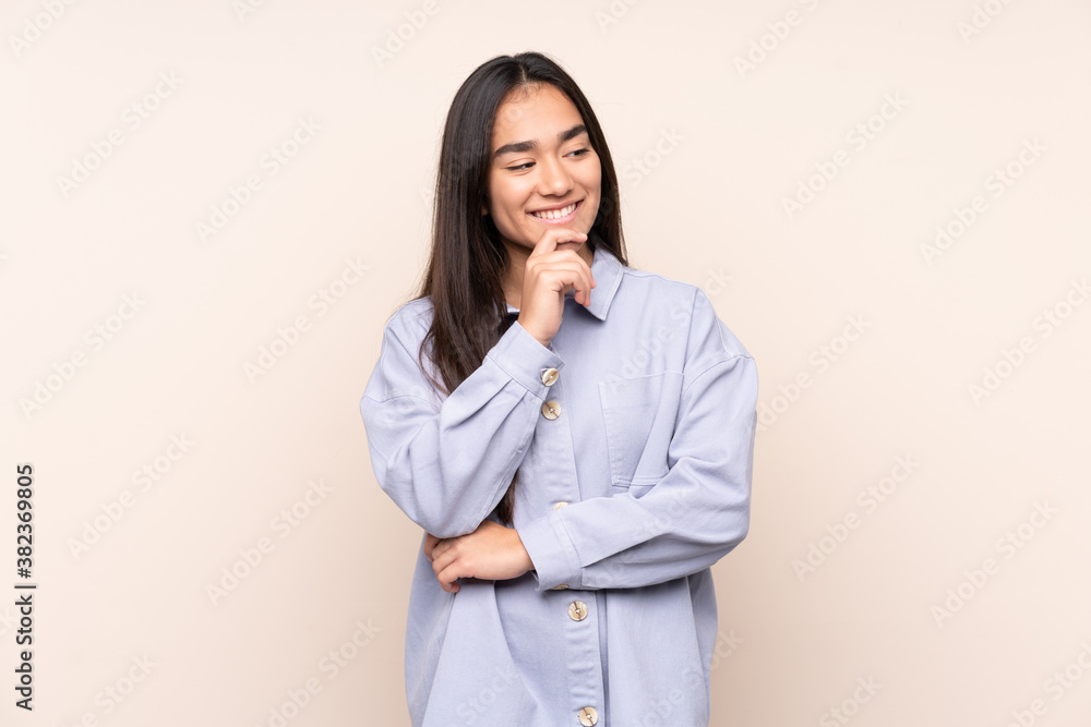 Young Indian woman isolated on beige background looking to the side and smiling Young Indian woman isolated on beige background looking to the side and smiling