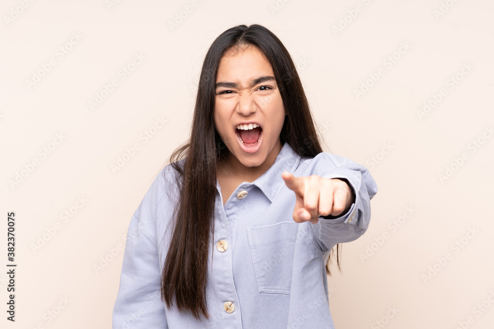 Young Indian woman isolated on beige background frustrated and pointing to the front Young Indian woman isolated on beige background frustrated and pointing to the front