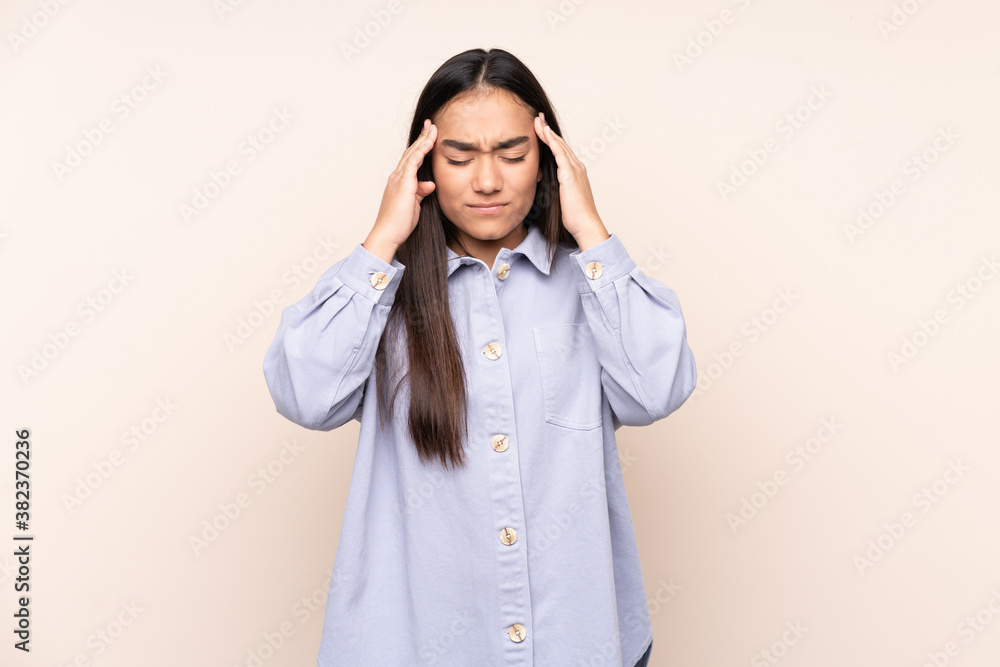 Young Indian woman isolated on beige background with headache