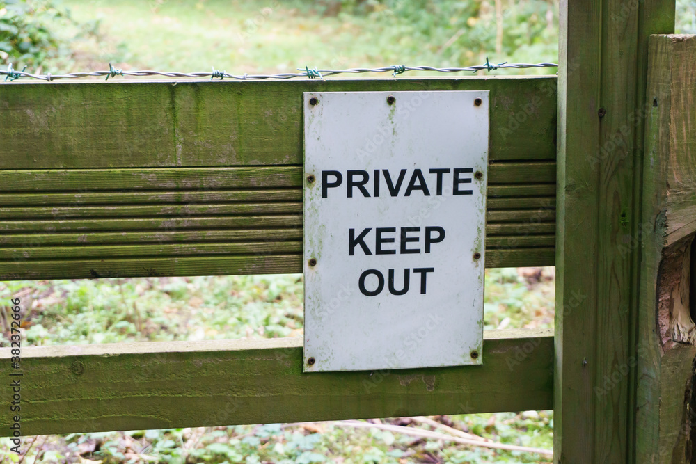 Obraz premium Private keep out sign on a gate with barbed wire on a forest trail