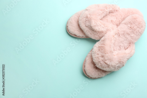 Pair of stylish soft slippers on turquoise background, flat lay. Space for text