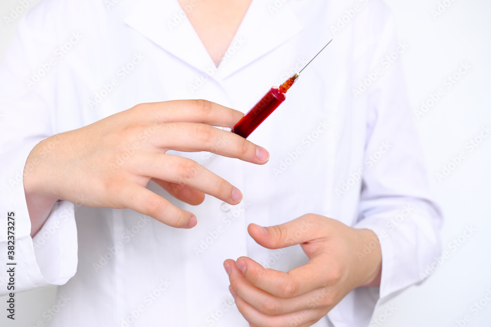 Doctor hand in a latex glove holds holds a syringe full of blood for analysis or blood transfusion Doctor hand in a latex glove holds holds a syringe full of blood for analysis or blood transfusion