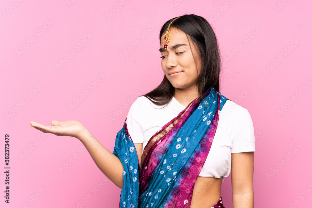 Young Indian woman with sari over isolated background holding copyspace with doubts Young Indian woman with sari over isolated background holding copyspace with doubts