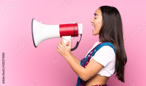 Young Indian woman with sari over isolated background shouting through a megaphone