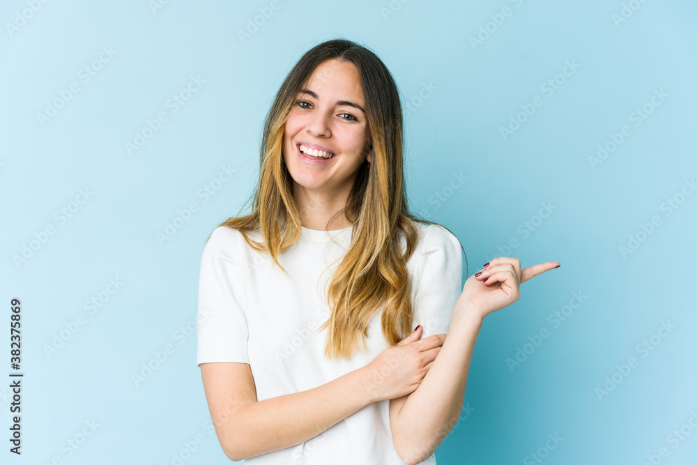 Young caucasian woman isolated on blue background smiling cheerfully pointing with forefinger away. Young caucasian woman isolated on blue background smiling cheerfully pointing with forefinger away.