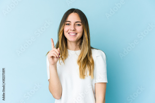 Young caucasian woman isolated on blue background showing number one with finger.