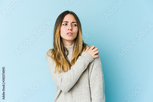 Young caucasian woman isolated on blue background having a shoulder pain.