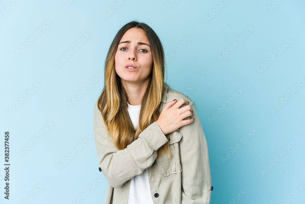 Young caucasian woman isolated on blue background having a shoulder pain. Young caucasian woman isolated on blue background having a shoulder pain.