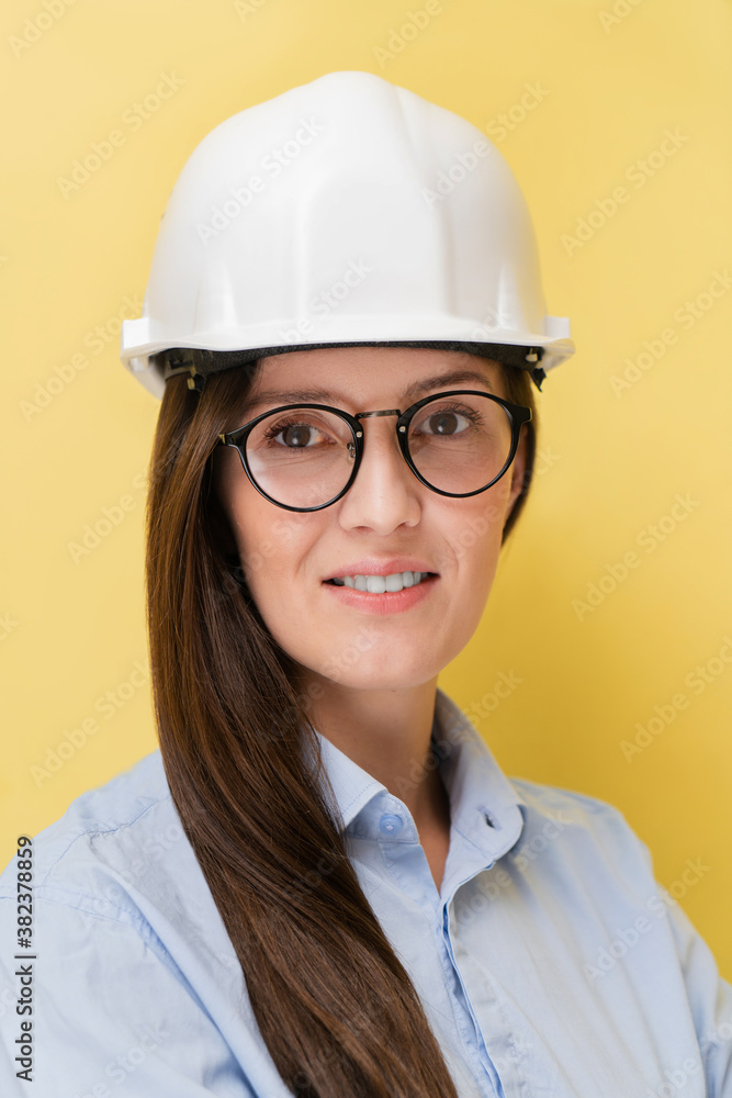 Portrait of smiling beautiful tatar woman engineer in construction helmet and glasses isolated on yellow background Portrait of smiling beautiful tatar woman engineer in construction helmet and glasses isolated on yellow background