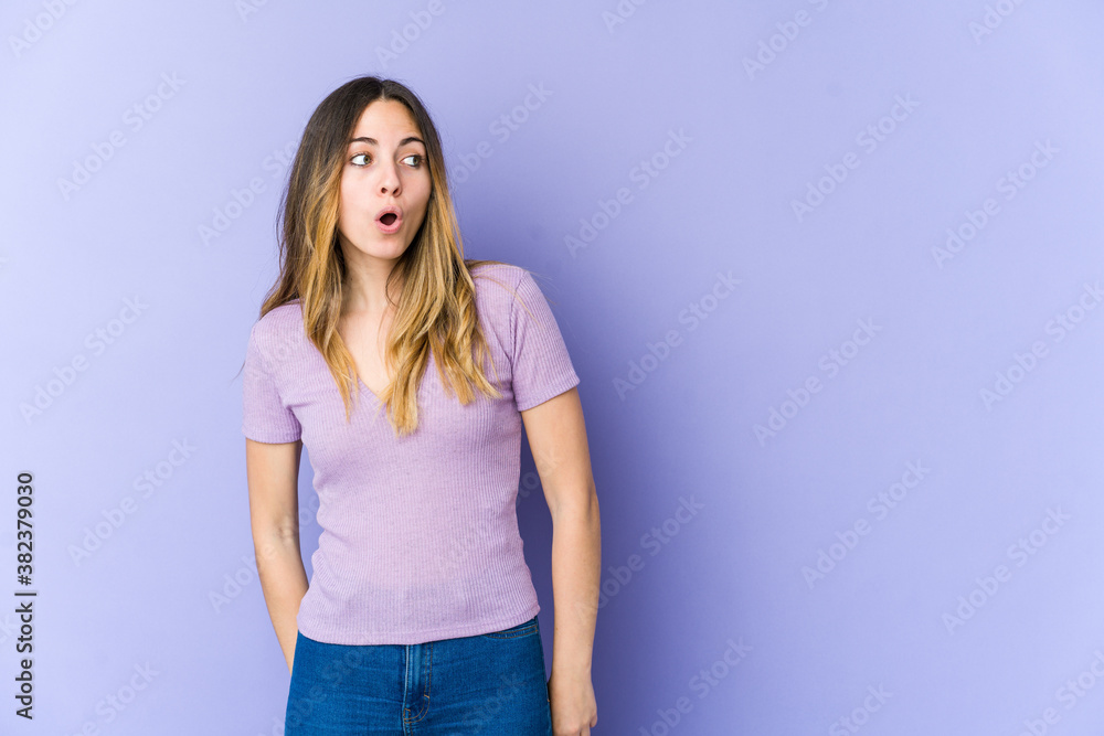 Young caucasian woman isolated on purple background being shocked because of something she has seen. Young caucasian woman isolated on purple background being shocked because of something she has seen.