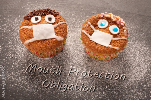 two  cup cakes decorated ,face with mouth cap warning