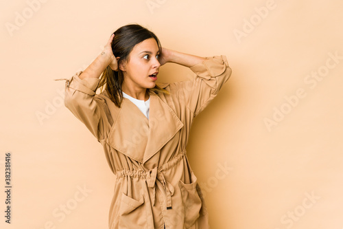 Young woman isolated on beige background screaming, very excited, passionate, satisfied with something.