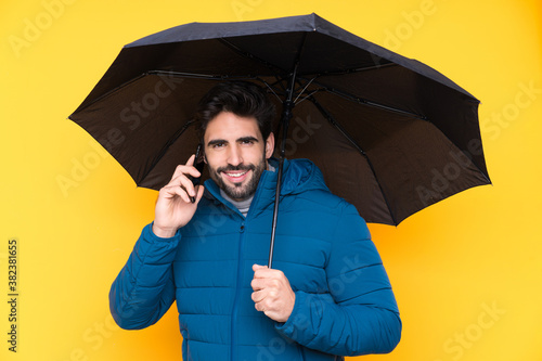 Man holding an umbrella over isolated yellow background © luismolinero