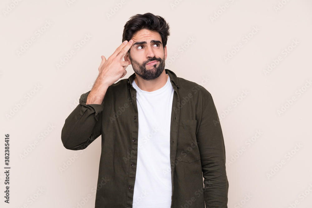 Young handsome man with beard over isolated background with problems making suicide gesture Young handsome man with beard over isolated background with problems making suicide gesture