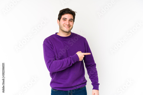 Young man isolated on white background smiling and pointing aside, showing something at blank space.