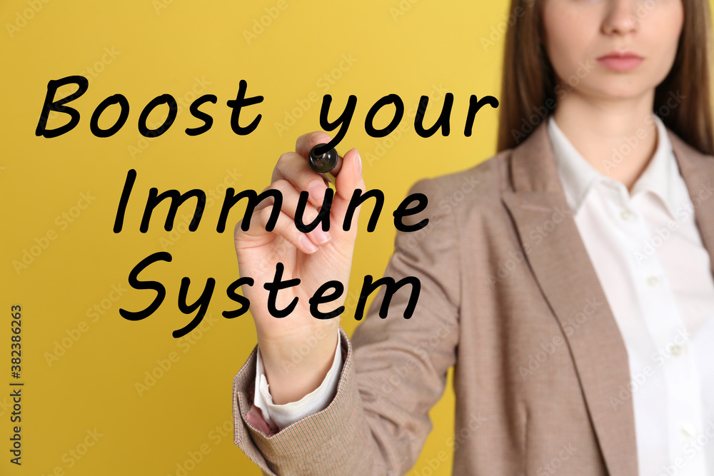 Boost your immune system. Woman writing text on transparent board, closeup Boost your immune system. Woman writing text on transparent board, closeup