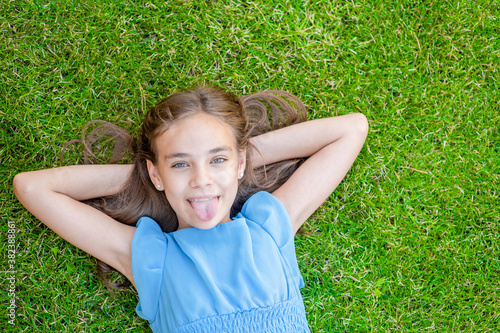 Happy teen girl lying on grass, top down view