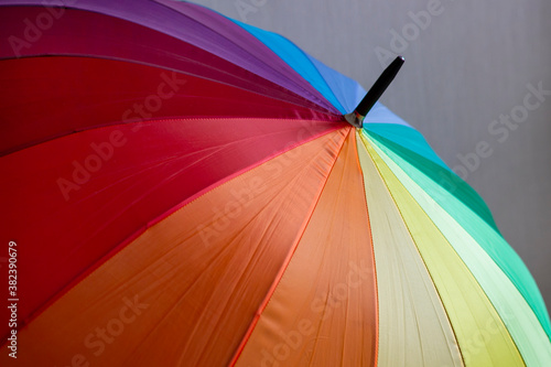 A multi-colored umbrella with stripes in rainbow colors  a symbol of the LGBT flag.