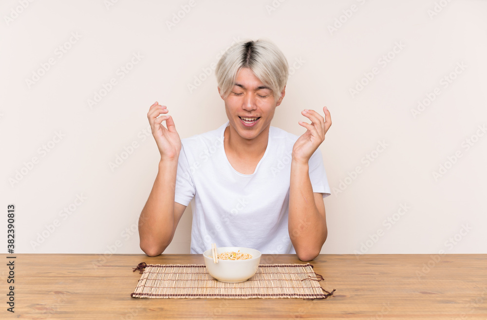 Young asian man with ramen in a table laughing Young asian man with ramen in a table laughing