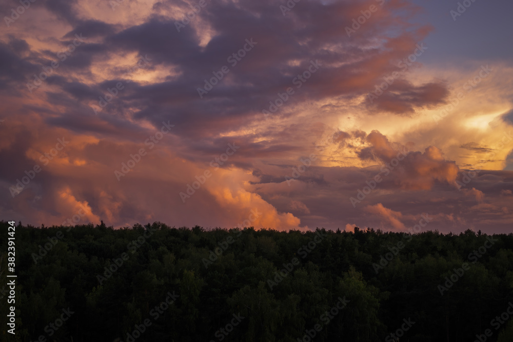 There are dramatic clouds in the dark sky as the sun sets. The sky is dominated by fuchsia, pink. There are dramatic clouds in the dark sky as the sun sets. The sky is dominated by fuchsia, pink.