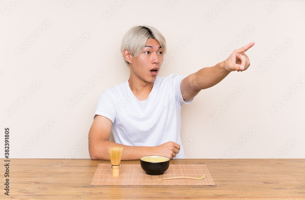 Young asian man with matcha tea in a table pointing away Young asian man with matcha tea in a table pointing away