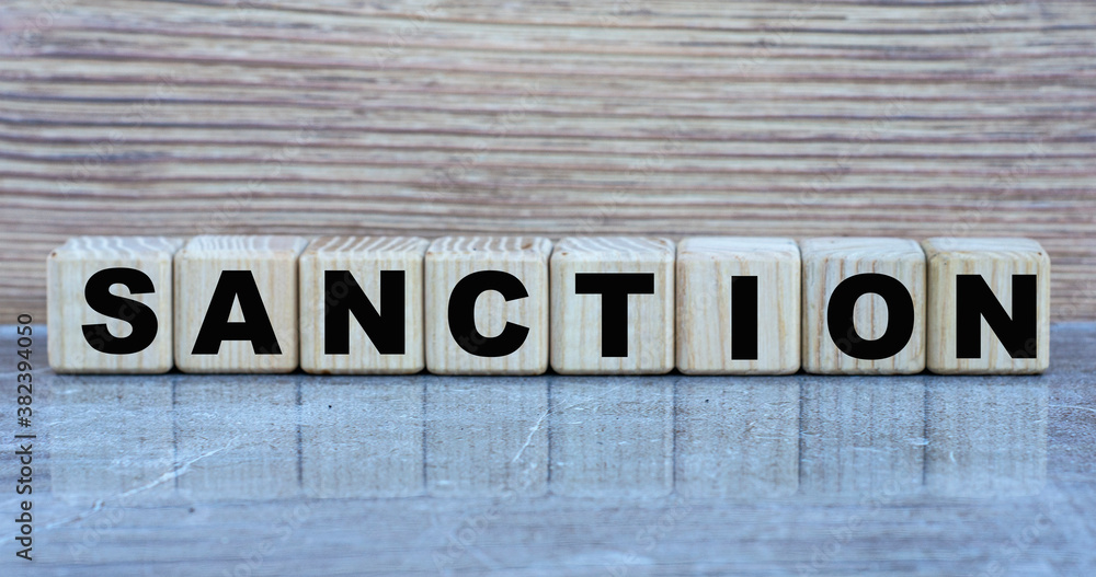 SANCTION - word on wooden cubes on a gray background SANCTION - word on wooden cubes on a gray background