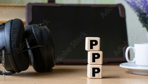 PPP -acronum on cubes on the background of the tablet, headphones and a white cup photo