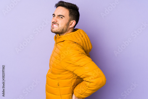 Young caucasian man isolated on purple background suffering a back pain.