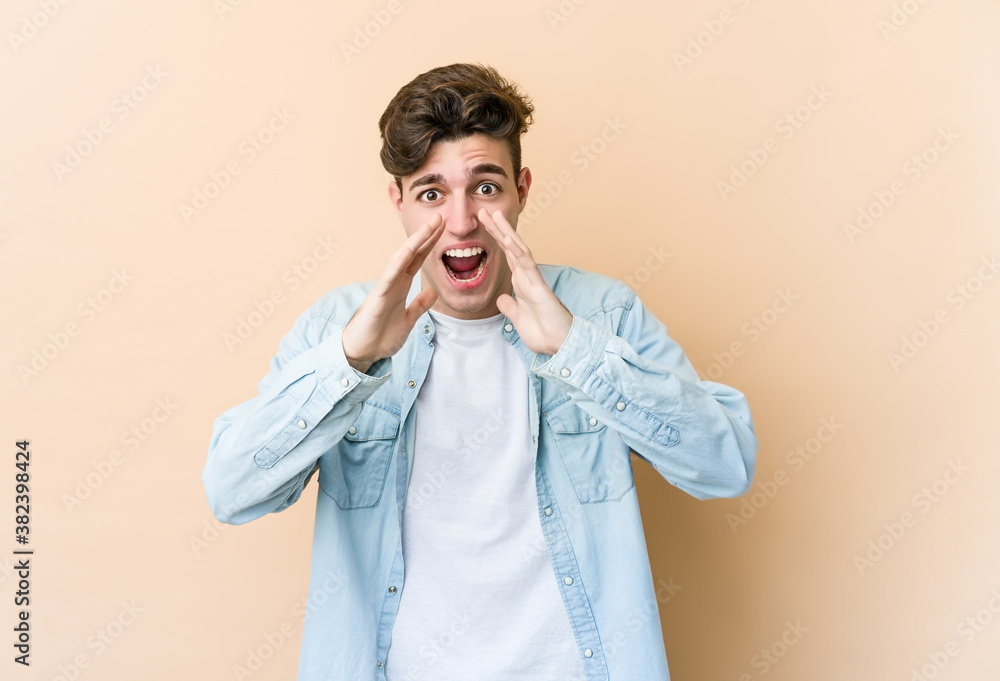 Young caucasian man isolated on beige background shouting excited to front. Young caucasian man isolated on beige background shouting excited to front.