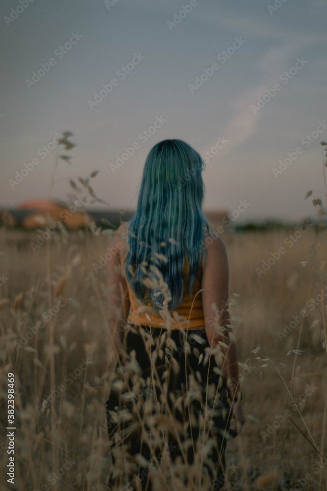 Chica con pelo azul de pie en el campo