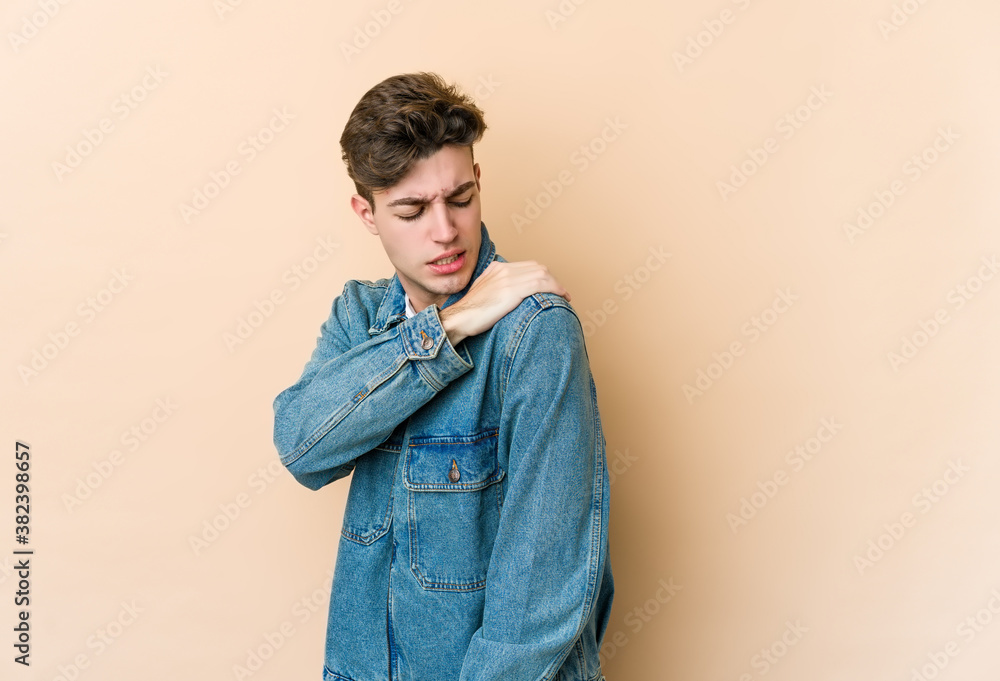 Young caucasian man isolated on beige background having a shoulder pain. Young caucasian man isolated on beige background having a shoulder pain.