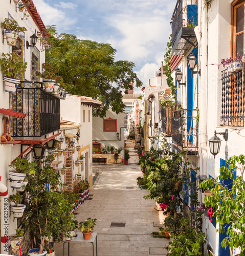 narrow alleys of the picturesque neighborhood of Santa Cruz with houses adorned with azulejos and many flowerpots outside.Mediterranean city of Alicante, Spain
