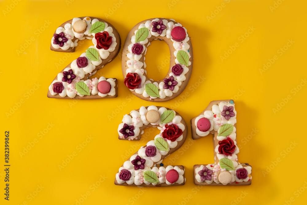 2021 cake decorated with flowers on yellow background. New year concept	
