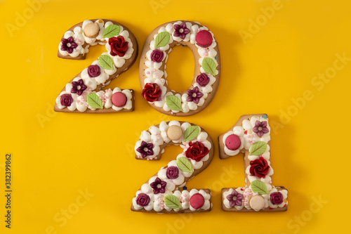 2021 cake decorated with flowers on yellow background. New year concept 