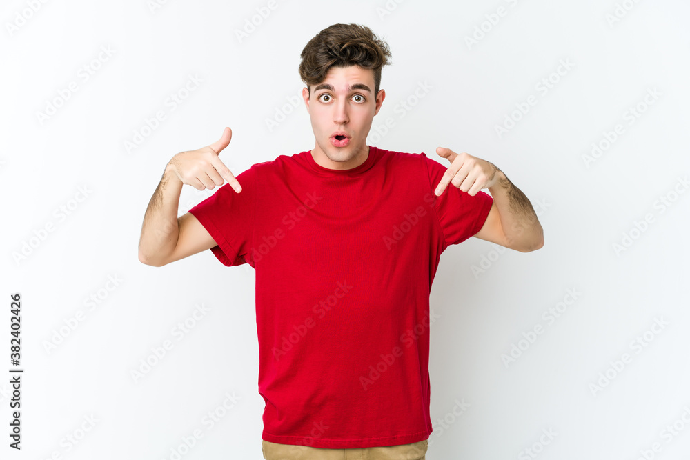 Young caucasian man isolated on white background points down with fingers, positive feeling. Young caucasian man isolated on white background points down with fingers, positive feeling.