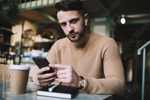 Young man browsing smartphone in cafe