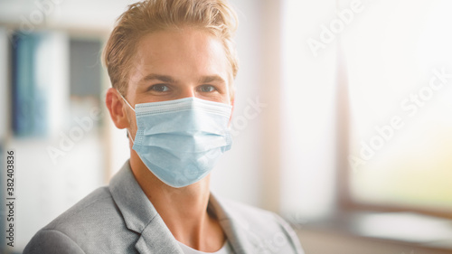 Portrait of the Handsome Stylish Young Man Wearing Protective Face Mask Inside. Blue Eyed Blond Haired Male Respects Quarantine Rules, Lockdown Measures and Safe Social Distancing. Looking at Camera
