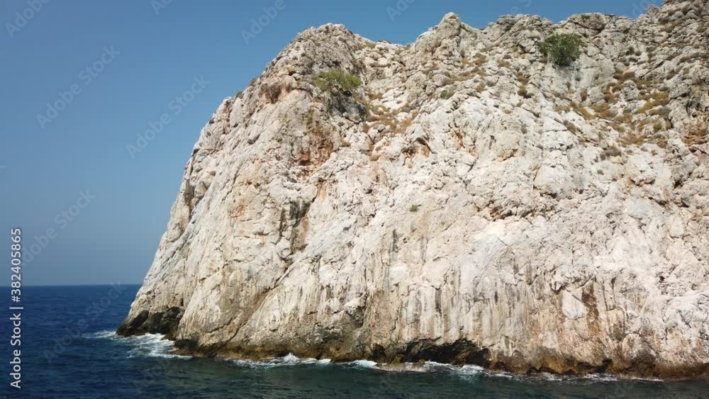 Ship in the sea goes along the rocky shore near the mountain Ship in the sea goes along the rocky shore near the mountain