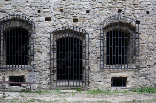 Historic jail, prison and jailhouse - old, historical and antique wall made of stone. Windows and doors with iron bars and grating. 