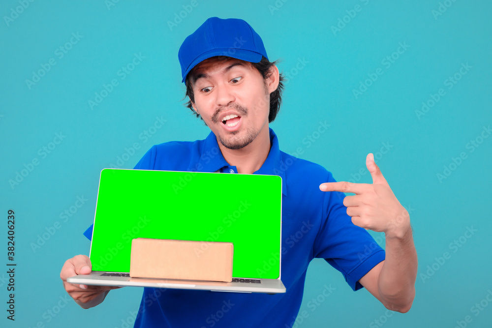 Delivery man isolated on blue background. Professional male employee courier in red cap, t-shirt holding laptop computer with blank empty screen. Service concept. Delivery man isolated on blue background. Professional male employee courier in red cap, t-shirt holding laptop computer with blank empty screen. Service concept.